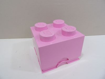 une brique Lego rose posée sur une table blanche