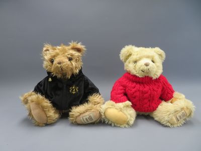 two teddy bears sitting next to each other on a gray background