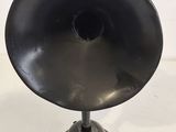 an old fashioned black speaker on a metal stand on a white surface