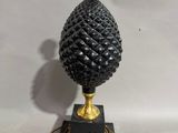 a black and gold table lamp with a pine cone on top