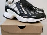 des baskets noires et blanches posées sur une boîte en carton, elle-même posée sur une surface blanche