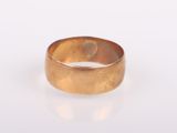 gros plan d'une bague en or sur une surface blanche