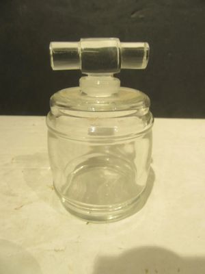 a small glass jar with a metal handle on a table