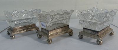 three glass vases on wheels on a white surface with a white background