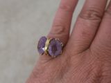 someone is holding a ring with a purple stone on it