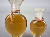 two bottles of perfume sitting next to each other on a table