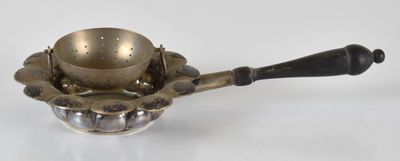 une théière ancienne en laiton, avec une anse noire sur un fond blanc