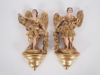 deux statues dorées représentant des anges, posées sur un fond blanc