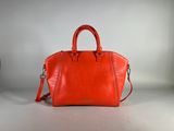 un sac à main rouge posé sur une table blanche