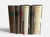 several books are lined up in a row on a white surface