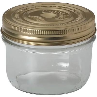 a glass jar with a gold lid on a white background