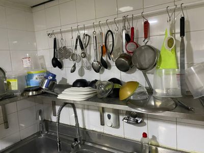 many pots and pans hanging on the wall above the sink