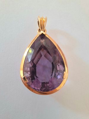 a close up of a purple stone pendant on a white surface