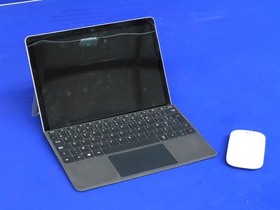un ordinateur portable et une souris posés sur une table bleue