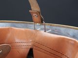 a brown leather bag with a wooden handle on a table