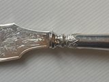 une cuillère en argent avec un manche en argent posée sur une table