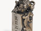 silver figurine of a lion on a block with chinese writing on it