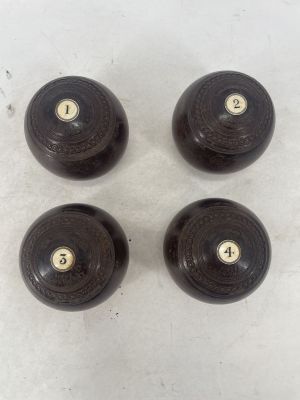 four black wooden knobs with brass numbers on them on a white surface