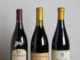 trois bouteilles de vin sont alignées sur une table en bois