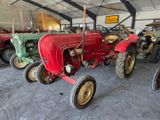 several old tractors are lined up in a large garage