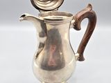 a silver coffee pot with a wooden handle on a table