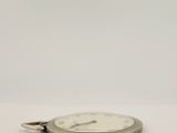 a silver pocket watch sitting on a white surface