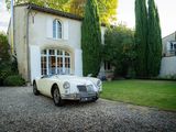 une photo d'une voiture de collection garée devant une maison