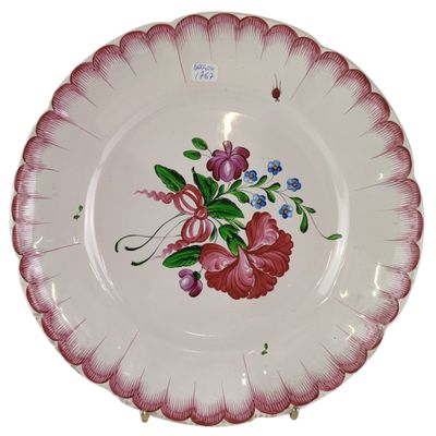une assiette décorée de fleurs, posée sur un socle