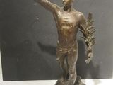 bronze statue of a man holding a plant in his right hand