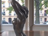 a statue of a woman sitting on a table in front of a window