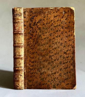 un vieux livre posé sur une table à côté d'un mur blanc