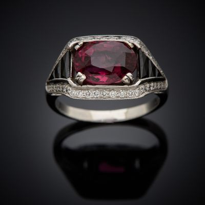 a close up of a ring with a ruby stone and diamonds