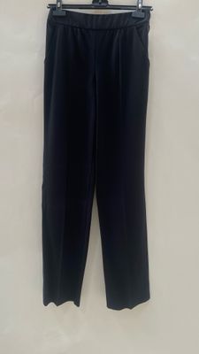 a black pants hanging on a hanger on a wall