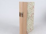 un vieux livre à la couverture marron posé sur une table blanche