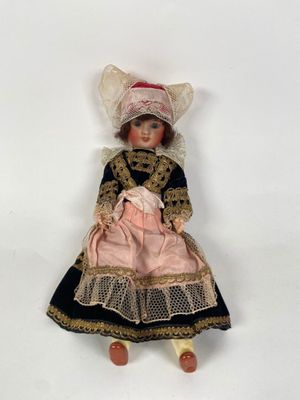 two dolls are sitting on a white surface one is wearing a pink dress and the other is wearing a black and gold dress
