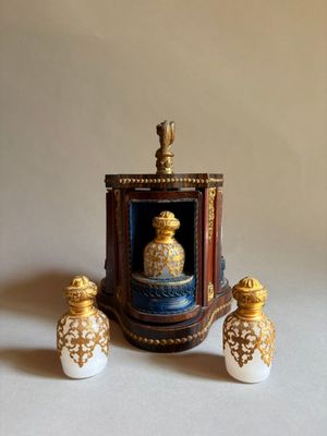 une figurine miniature représentant un flacon de parfum et deux salières posées sur une table