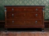 une commode dans une pièce au papier peint vert