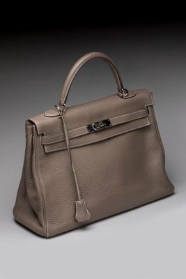 a beige leather handbag with a metal handle on a gray background