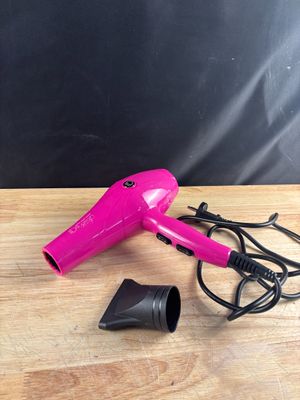 un sèche-cheveux rose posé sur une table en bois