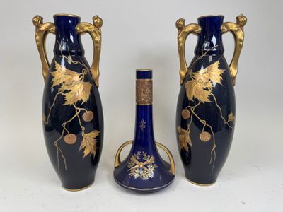 two blue vases with gold leaf designs and a cork stopper