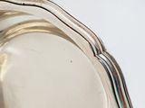 a close up of a silver plate with a handle on a table