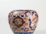 a blue and orange vase sitting on a white surface