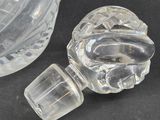a clear glass bottle with a stopper next to it
