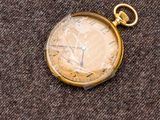 une montre de poche en or posée sur un tissu marron