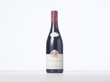 a bottle of red wine sitting on top of a white table