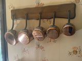 plusieurs casseroles et poêles suspendues à un support en bois dans une cuisine