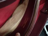 a person holding a red purse with a gold zipper