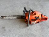 an orange chainsaw sitting on the ground in a garage