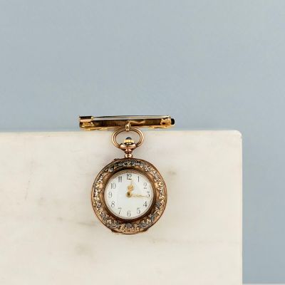 un gros plan d'une petite montre de poche en or posée sur un bloc de marbre