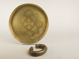 une image représentant une assiette en or posée sur un socle en bois, sur fond blanc
